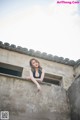 A woman leaning on the edge of a building.