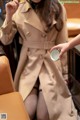 A woman in a trench coat holding a cup of coffee.