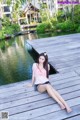 A woman sitting on a wooden dock next to a body of water.