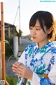 A woman in a blue and white kimono holding a flower.