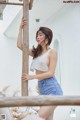 A woman leaning against a wooden pole on a balcony.