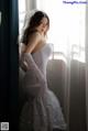 A woman in a wedding dress leaning against a window.