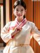 A woman in a white and pink hanbok posing for a picture.