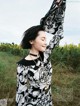 A woman in a black and white dress standing in a field.