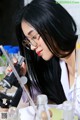 A woman in a lab coat looking through a microscope.