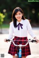 A woman in a school uniform standing next to a bike.