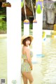 A woman in a yellow and white bikini standing in the water.