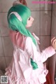 A woman with long green hair wearing a pink dress.