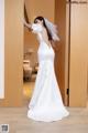 A woman in a white wedding dress standing in front of a door.