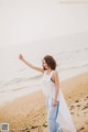 A woman standing on a beach with her arms outstretched.