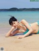 A woman in a blue bikini laying on the beach.