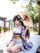 A woman in a kimono sitting on a bed holding an umbrella.