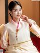 A woman in a white and pink hanbok sitting on a red chair.