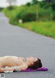 A woman laying on the side of a road in the rain.